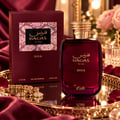 RASASI Hawas Diva by Rasasi 100ml EDP — Botol minyak wangi merah pekat bertudung emas bertekstur, bersama kotak merah marun sepadan bermotif kulit ular, di atas dulang cermin bersama gelang emas dan kelopak mawar.