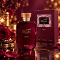 RASASI Hawas Diva by Rasasi 100ml EDP — Botol minyak wangi merah gelap mewah dengan penutup emas, dipamerkan bersama kotak sepadan dan dikelilingi bunga mawar merah serta lampu bokeh.
