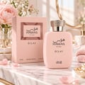 RASASI Hawas Eclat by Rasasi 100ml EDP — Pink perfume bottle and box with a textured gold cap, displayed on a marble surface with pink rose petals and a bouquet of pink peonies in the background.