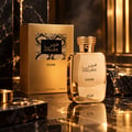 RASASI Hawas Elixir — Gold perfume bottle and box with snake print detail, set on a dark reflective surface with textured rocks and golden light.