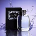 Rasasi Hawas For Him Eau De Parfum 100ml — A black box with a snakeskin pattern and the Hawas logo sits next to a clear glass perfume bottle with a silver ribbed cap, set against a purple background with water splashes. | Rasasi Hawas For Him Eau De Parfum 100ml — Kotak hitam dengan corak kulit ular dan logo Hawas