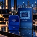 RASASI Hawas Gold Digger by Rasasi 100ml EDP — Botol dan kotak minyak wangi biru dipamerkan di atas permukaan marmar dengan latar belakang langit bandar pada waktu malam.