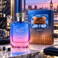 RASASI Hawas London by Rasasi 100ml EDP — Botol minyak wangi kaca gradien biru dan merah jambu dengan penutup perak seperti ular, diletakkan di atas permukaan marmar dengan kotak biru sepadan di latar belakang. Jam tangan dan butang lengan baju kelihatan di sebelah kiri.