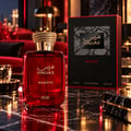 Rasasi Hawas Majestic EDP — Red glass perfume bottle with gold cap, next to its black textured box, set against a dark, fiery background with rocky elements.