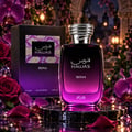RASASI Hawas Reina by Rasasi 100ml EDP — Kotak hitam dengan gradien ungu dan corak berhias di sebelah botol minyak wangi kaca gradien ungu bertudung perak bertekstur, dikelilingi orkid ungu dan mawar merah di atas permukaan marmar.