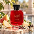 RASASI Hawas Rouge by Rasasi 100ml EDP — Red glass perfume bottle with black braided cap, surrounded by sliced pears, white flowers, and vanilla pods on a marble surface with water.