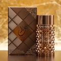 Ard Al Zaafaran Jazzab Gold Eau De Parfum 100ml — A gold-toned perfume bottle with a diamond-patterned glass body and a fluted cap, placed next to its matching textured brown and gold box on a reflective surface with a golden, textured background. | Ard Al Zaafaran Jazzab Gold Eau De Parfum 100ml — Botol minyak wangi