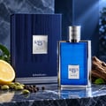 Khadlaj Karus Blu Spice by Khadlaj 100ml EDP Men — Blue ribbed perfume bottle with silver cap, next to its matching blue box. Lemon slice, cardamom pods, and peppercorns are scattered on a dark marble surface.