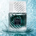 Lattafa Khamrah Waha Lattafa Perfumes 100ml EDP — A clear glass perfume bottle with a textured design and a dark green liquid inside, surrounded by splashing water and droplets against a light blue, rippling water background. | Lattafa Khamrah Waha Lattafa Perfumes 100ml EDP — Botol minyak wangi kaca jernih dengan