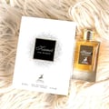 Maison Alhambra Kismet for Women 100ml — A white perfume box and a clear glass bottle with golden liquid are placed on a fluffy white background. | Maison Alhambra Kismet for Women 100ml — Kotak minyak wangi putih dan botol kaca jernih berisi cecair keemasan diletakkan di atas latar belakang putih berbulu.