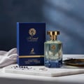 Maison Alhambra Kismet Lunar Magic 100ml — A blue box and a faceted glass perfume bottle with a gold cap sit on a marble surface with scattered lavender sprigs and a ring | Maison Alhambra Kismet Lunar Magic 100ml — Kotak biru dan botol minyak wangi kaca berfaset dengan penutup emas diletakkan di atas permukaan marmar