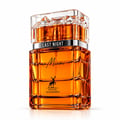 Maison Alhambra Last Night in Miami — Amber liquid in a clear, faceted glass bottle with a crystal-like cap. Features a silver band with 'LAST NIGHT' text and a deer logo with 'MAISON ALHAMBRA' text.