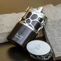 Lattafa Lattafa Qimmah Eau De Parfum for Men 100ml — Botol wangian gelap dengan perincian perak berukir, diletakkan di atas batu kelabu bersama penutupnya yang berkilat.
