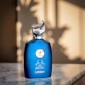 Maison Alhambra Leyden by Maison Alhambra Eau De Parfum 100ml — A blue perfume bottle with a silver cap and a circular emblem featuring a deer and horses, placed on a marble surface with soft shadows in the background. | Maison Alhambra Leyden by Maison Alhambra Eau De Parfum 100ml — Botol minyak wangi biru dengan