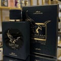 Lattafa Malik Al Tayoor Concentrated 100ml by Lattafa — A dark blue perfume bottle with a gold eagle emblem and cap sits next to its matching dark blue box with a gold eagle design. | Lattafa Malik Al Tayoor Concentrated 100ml by Lattafa — Botol minyak wangi biru gelap dengan lambang helang emas dan penutup duduk di