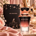 Maison Alhambra Mia Dolcezza by Maison Alhambra 100ml EDP Women — Black and rose gold perfume bottle and box with floral motifs, displayed with pink roses and silk fabric.