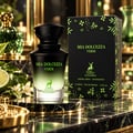 Maison Alhambra Mia Dolcezza Verde — Black and green gradient perfume bottle with deer logo, next to its matching green floral patterned box, on a marble surface with lime and flowers.