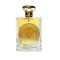 Ard Al Zaafaran Mithqal 100ml by Ard Al Zaafaran — A clear glass perfume bottle with a gold cap and a large circular gold emblem on the front, containing Arabic script and winged designs. The liquid inside is golden yellow. | Ard Al Zaafaran Mithqal 100ml oleh Ard Al Zaafaran — Botol minyak wangi kaca jernih dengan