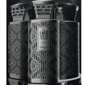 Zimaya Modhesh Noble 100ml by Zimaya — Three metallic perfume bottles with intricate geometric cutouts and ornate caps, arranged closely together in a studio setting. | Zimaya Modhesh Noble 100ml by Zimaya — Tiga botol minyak wangi metalik dengan potongan geometri yang rumit dan penutup berhias, disusun rapat bersama