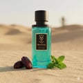 Bujairami Non Stop by Bujairami 100ml Extrait — Teal glass perfume bottle with black cap, set on sand dunes with dates and mint leaves in the foreground.
