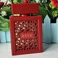 Rave Now Rouge Perfume EDP 100ml by RAVE — A red perfume bottle with a geometric lattice design on the front, featuring the word "RAVE" in gold lettering, set against a blurred background of green foliage and red berries. | Rave Now Rouge Perfume EDP 100ml by RAVE — Botol minyak wangi merah dengan reka bentuk kratis