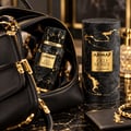 Armaf Old Money by Armaf 100ml EDP Unisex — Black textured bottle with gold accents inside a black leather handbag, next to its cylindrical packaging and a gold bracelet.