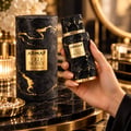 Armaf Old Money by Armaf 100ml EDP Unisex — A hand holds a textured black and gold perfume bottle, with its matching cylindrical box and a small dish of pearls in the foreground.