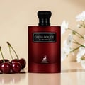 Maison Alhambra Opera Rouge Eau de Parfum — A deep red perfume bottle with a black cap and a label reading 'OPERA ROUGE EAU DE PARFUM' and a deer logo at the bottom, placed next to fresh cherries and white flowers. | Maison Alhambra Opera Rouge Eau de Parfum — Botol minyak wangi merah pekat bertudung hitam dengan
