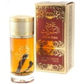 Ard Al Zaafaran Oud Al Turas 100ml — A clear glass perfume bottle with golden ribbed cap and amber liquid, containing a dark oud stick, stands next to its ornate red and gold patterned box. | Ard Al Zaafaran Oud Al Turas 100ml — Botol kaca jernih dengan penutup bergaris emas dan cecair ambar, mengandungi kayu oud