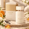 Khadlaj Panache Angel Dust — Perfume bottle and box with embossed floral design, surrounded by orange slices, jasmine flowers, vanilla beans, and amber-colored resin pieces on a marble surface.