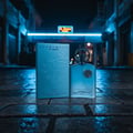 Afnan Supremacy In Heaven — Blue perfume bottle and box on wet cobblestone street at night with neon lights