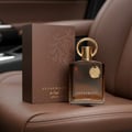 Afnan Supremacy In Oud — Brown box and glass bottle with gold accents on brown leather car seat