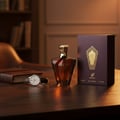 Afnan Turathi Brown — Amber perfume bottle and box on a wooden desk with a leather-bound notebook and wristwatch