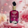 Al Wataniah Sabah Al Ward — A deep pink perfume bottle with gold accents sits on pink petals, with two miniature figures