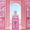 Ard Al Zaafaran Bab Al Wardi — Pink ornate doorway with a key design on a perfume bottle, set against a desert landscape.