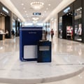 Ard Al Zaafaran Desert Sultan Sapphire — Blue glass perfume bottle and matching box on a marble table in a mall.