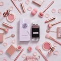 Ard Al Zaafaran Zahoor Francee — Pink makeup, rose petals, brushes, and perfume bottle arranged on a marble surface.