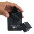 Armaf Club De Nuit Urban Elixir — Hand holding black perfume bottle with dice-shaped cap nearby, white background