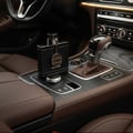 Armaf Dubai Nights Midnight — Black perfume bottle with gold accent charm sits on car center console