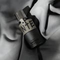 Armaf Hunter Intense — Black perfume bottle with a textured tan band and silver cap, resting on draped grey fabric.