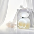 Grandeur Candy White by Grandeur – 100 ml for Women, a white perfume bottle with a faceted crystal-like cap, placed next to a white gift box tied with a satin ribbon, with sheer white curtains in the background.