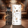 Grandeur Voyage Exclusif by Grandeur Elite – Dark glass perfume bottle and white cylindrical box with shattered gold accents and swirling smoke effect, set on a wooden surface.