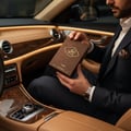 Afnan Afaq Gold by Lattafa EDP 100 ml Unisex — Man in suit holding brown perfume box with gold Arabic text inside luxury car