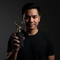 Lattafa Al Noble Ameer — Man holding black perfume bottle with gold deer head stopper against dark background