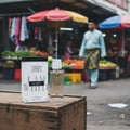 Lattafa Ana Abiyedh — Perfume bottle and box on a wooden crate, with a blurred market scene in the background.
