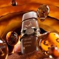 Lattafa Asad Bourbon — Hand holding brown perfume bottle with gold accents and Arabic script in a shopping mall
