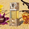 Lattafa Atheeri — Perfume bottle on sand with honeycomb, vanilla pods, and a purple flower.