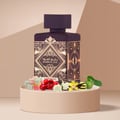 Lattafa Badee Al Oud Amethyst — Purple bottle with gold geometric design, surrounded by colorful candies, cherries, vanilla