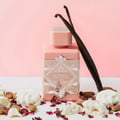 Lattafa Badee Al Oud Noble Blush — Pink bottle with geometric pattern, vanilla pods, almonds, and meringue pieces on a pink