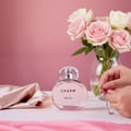 Lattafa Charm 100ml EDP for Women by LaMuse — Pink perfume bottle with 'CHARM' text, next to pink roses and a hand holding a